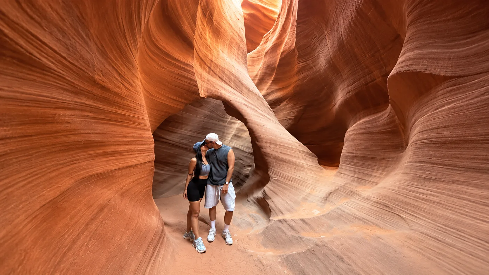 Visitors walking through a narrow sandstone canyon scene